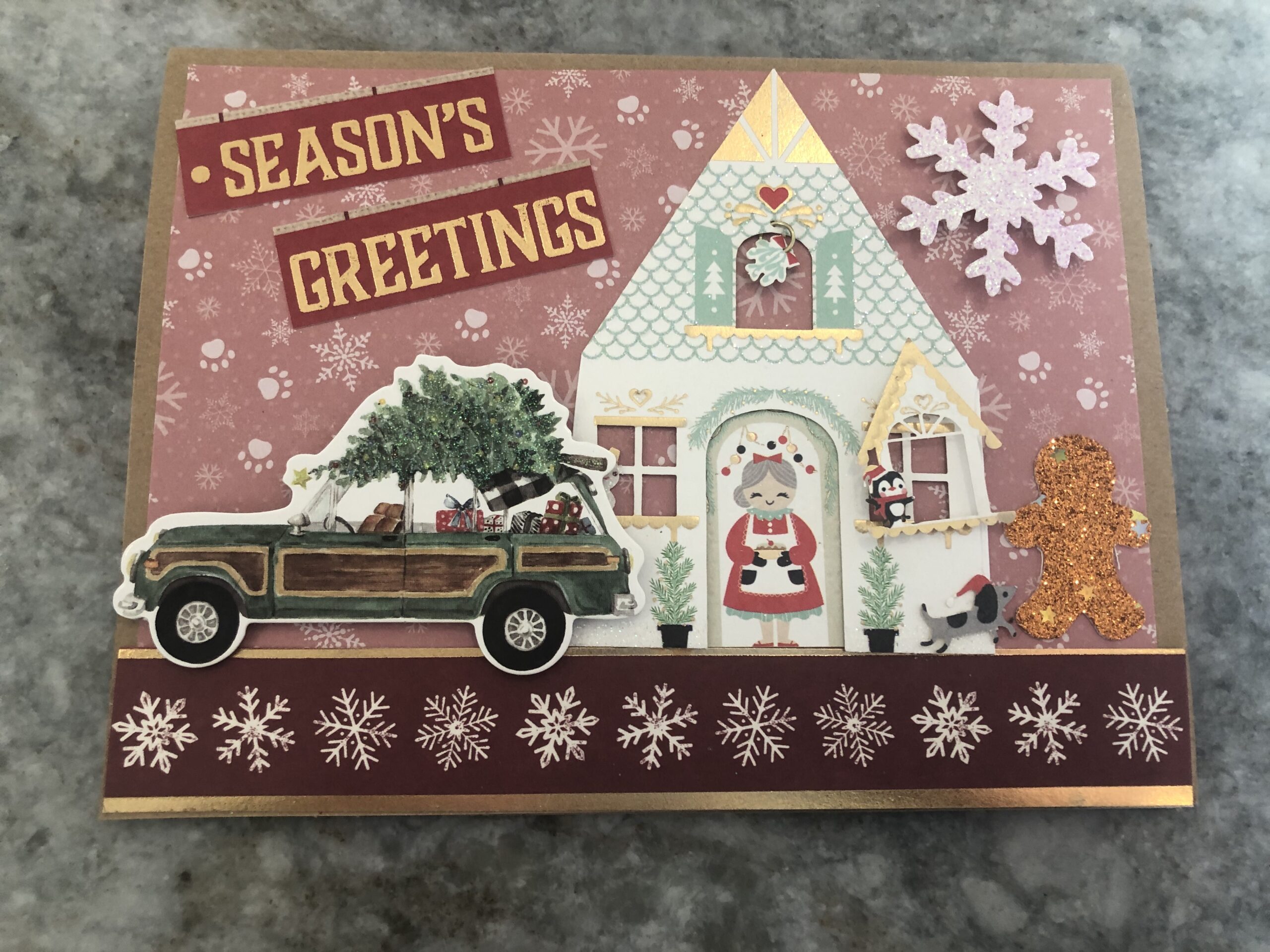 Home made Christmas card using recycled materials... features a car with a wreath on it, a house decorated, and "seasons greetings"